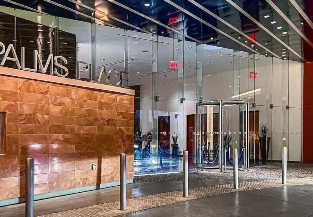 A modern hotel entrance with a glass facade, a reception desk, and a revolving door.