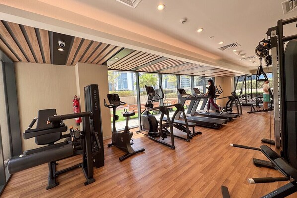 A modern gym with treadmills, elliptical machines, and weightlifting equipment.