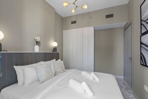 Een moderne hotelkamer met een groot bed, nachtkastje, spiegel en een kledingkast.