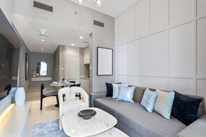 A modern living room with a grey sofa, a white coffee table, and a dining area with a round table and chairs.