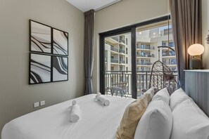 A hotel room with a large bed, a view of the building's balconies, and a modern abstract painting on the wall.