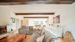 Ein geräumiges Wohnzimmer mit einem Holztisch, gestreiften Sofas und einem weißen Schrank.