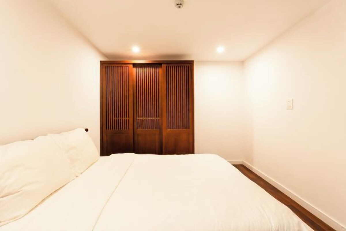 Ein Schlafzimmer mit einem Bett, einem Holzschrank und einer Deckenleuchte.