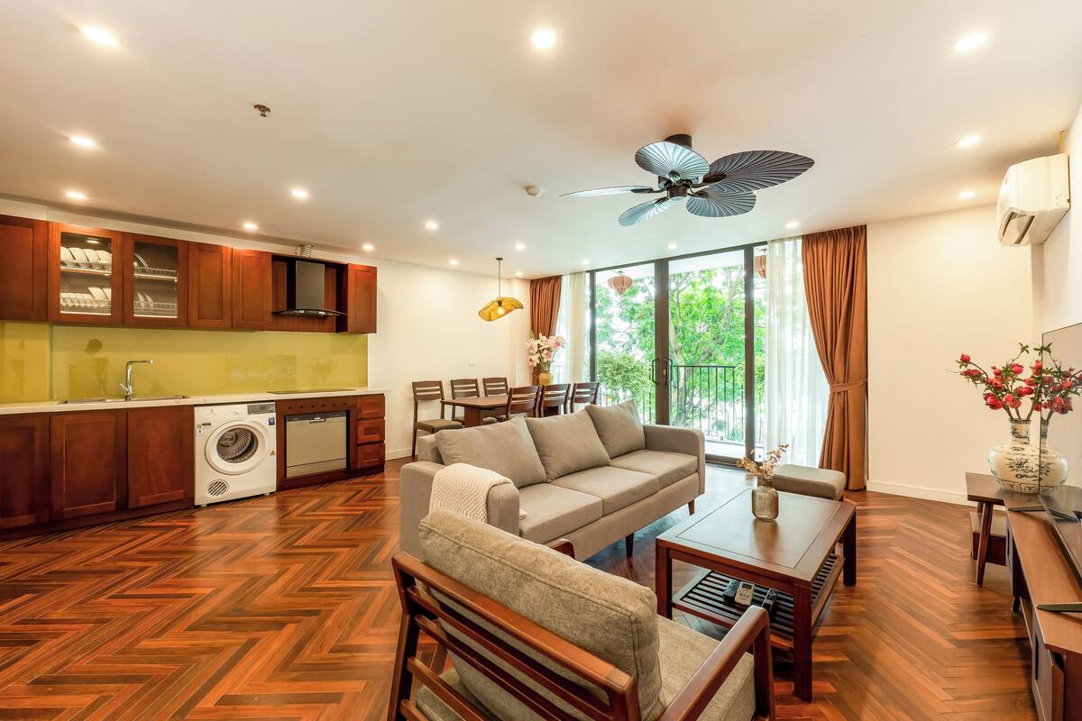 Eine moderne Küche mit Holzschränken, einer integrierten Waschmaschine und einem Essbereich mit Sofa und Tisch.
