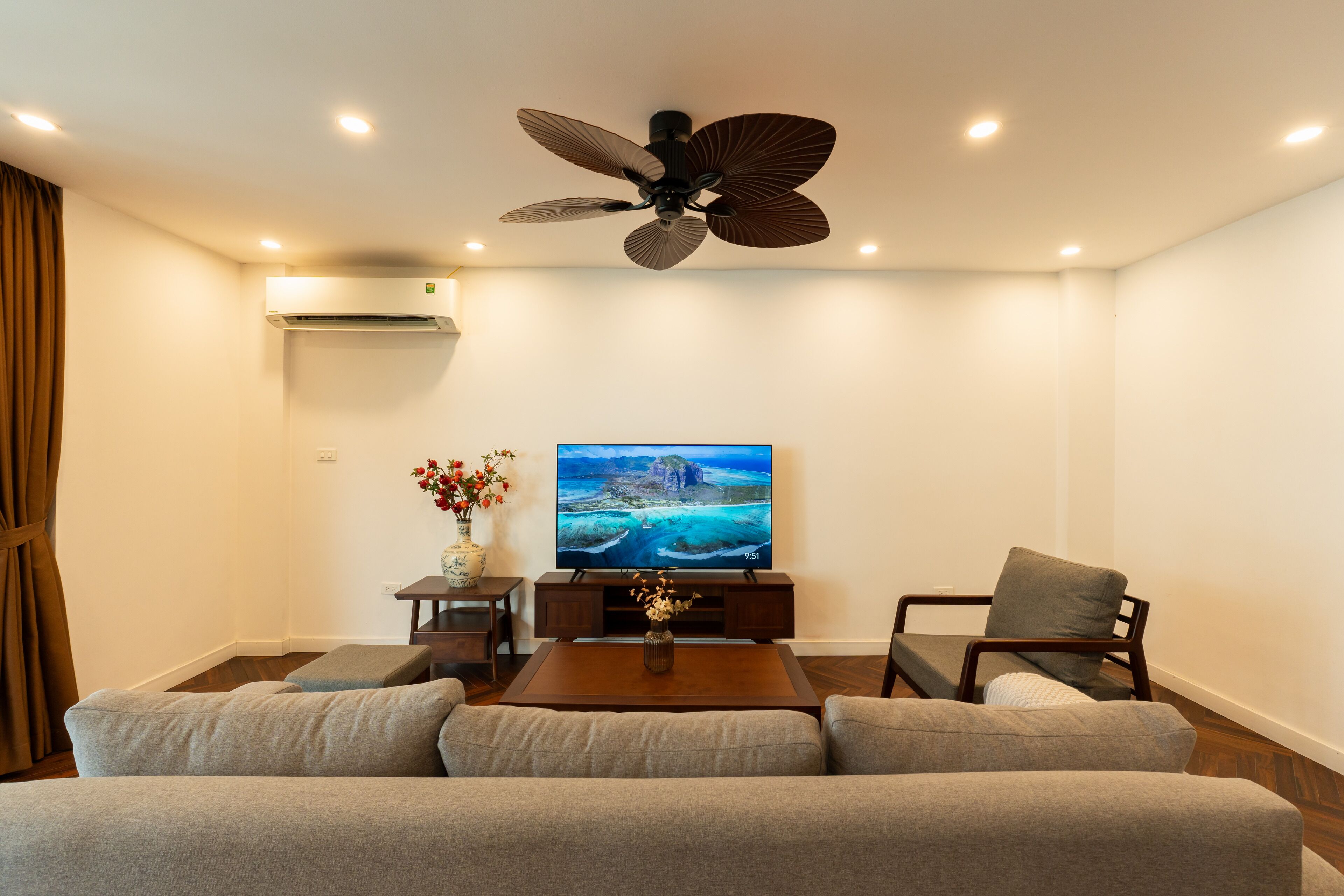 A living room with a sofa, a coffee table, a TV, and a ceiling fan.