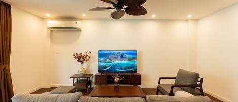 A living room with a sofa, a coffee table, a TV, and a ceiling fan.