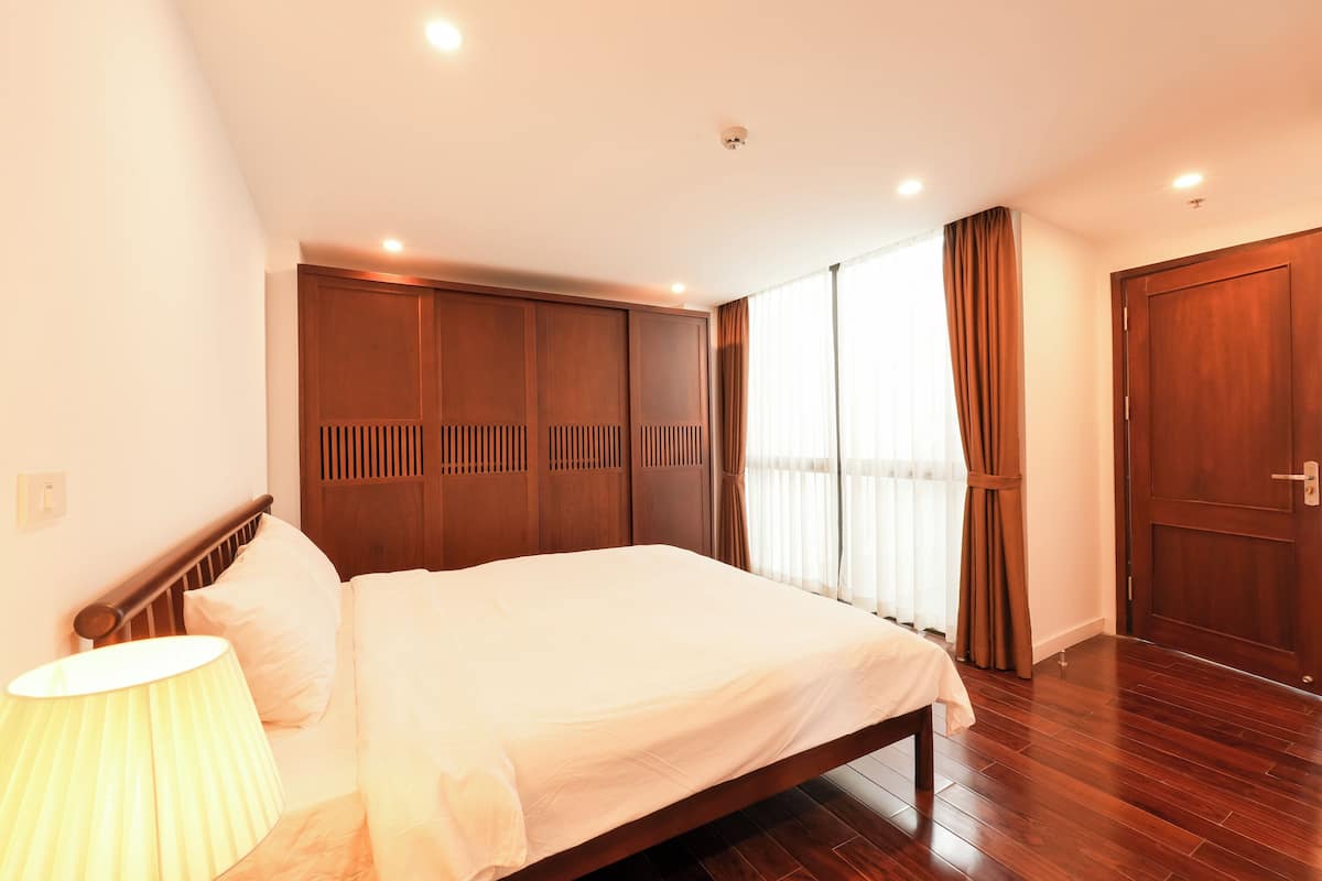 Ein Hotelzimmer mit einem großen Bett, einem Holzschrank und einem Fenster mit Vorhängen.