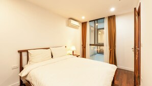 A hotel room with a bed, bedside lamp, air conditioning unit, and a view of the outside through a glass door. - Nine Housing West lake 136 Vu Mien (Hanoi)