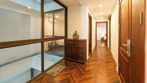 A hallway with wooden flooring, a glass door, and a wooden cabinet. - Nine Housing West lake 136 Vu Mien (Hanoi)