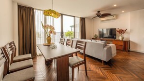 A modern living room with a dining area, wooden flooring, a sofa, TV, and a ceiling fan. - Nine Housing West lake 136 Vu Mien (Hanoi)