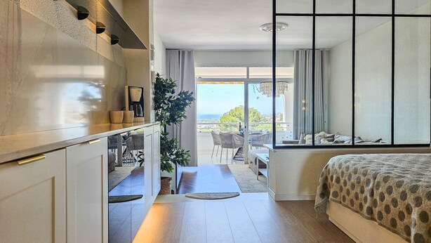 Una habitación de hotel moderna con una cama grande, un comedor y vista al mar.