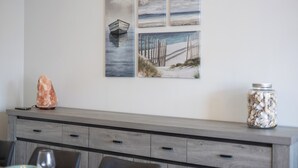 Una pared con cuatro cuadros que muestran un barco, una playa, un cielo nublado y un muelle de madera.