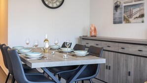 Una mesa de comedor dispuesta con platos, vasos y una botella, rodeada de sillas.