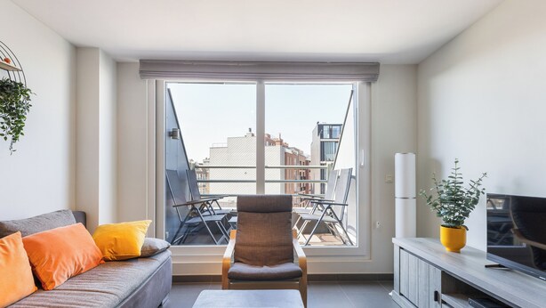 Una sala de estar moderna con un sofá, un sillón y un mueble para televisión.