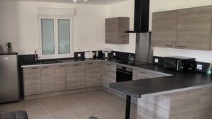 Una cocina moderna con una isla central, armarios empotrados y una campana extractora de acero inoxidable.