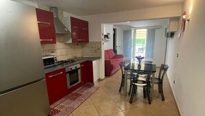 Une cuisine moderne avec des meubles rouges, un réfrigérateur en acier inoxydable et un coin repas comprenant une table et des chaises.