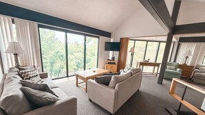 A modern living room with a sofa, coffee table, and a dining area.