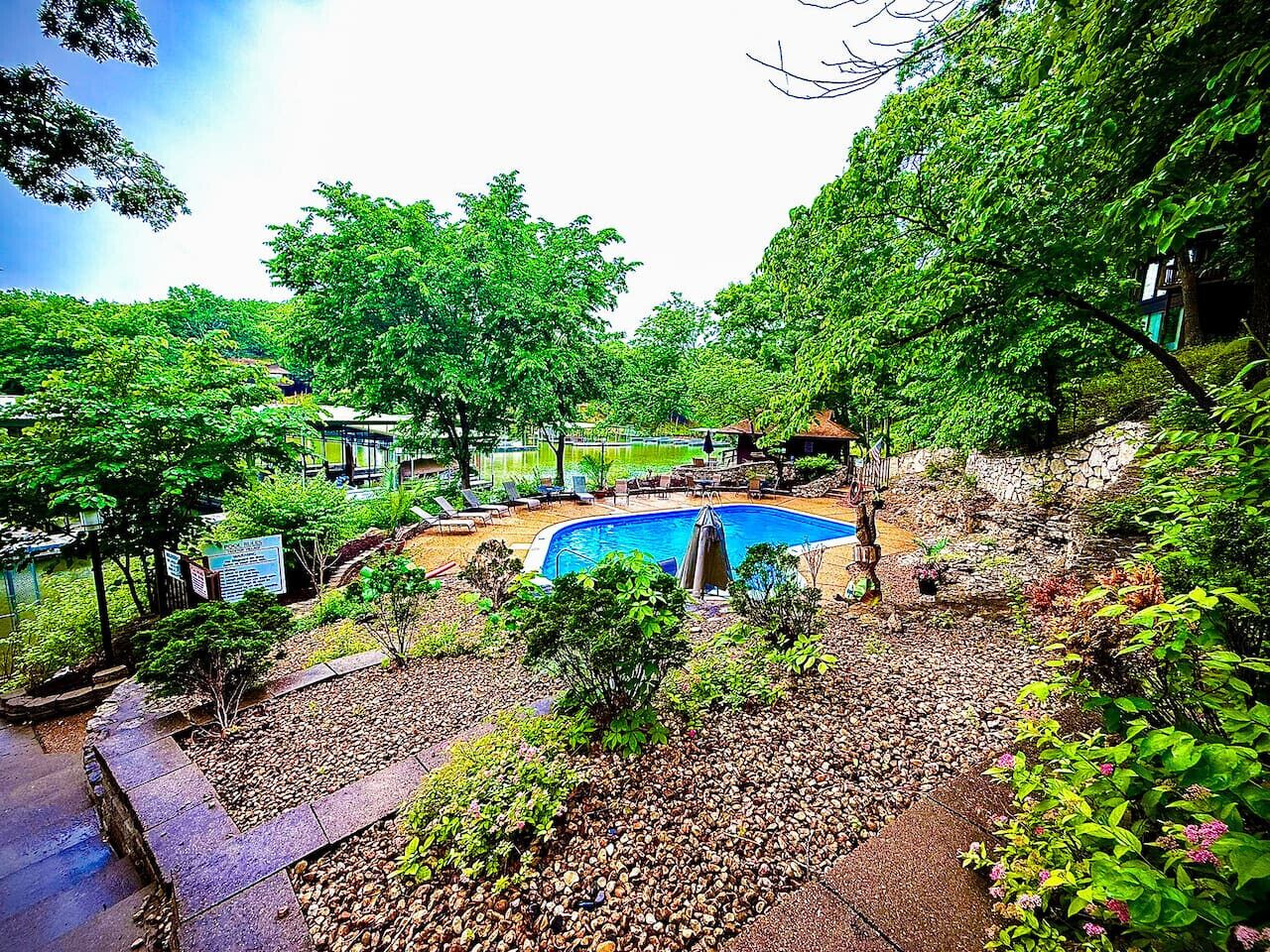 Una piscina rodeada de exuberante vegetación y senderos de piedra.