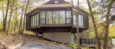 A cabin with a large glass window, surrounded by trees.