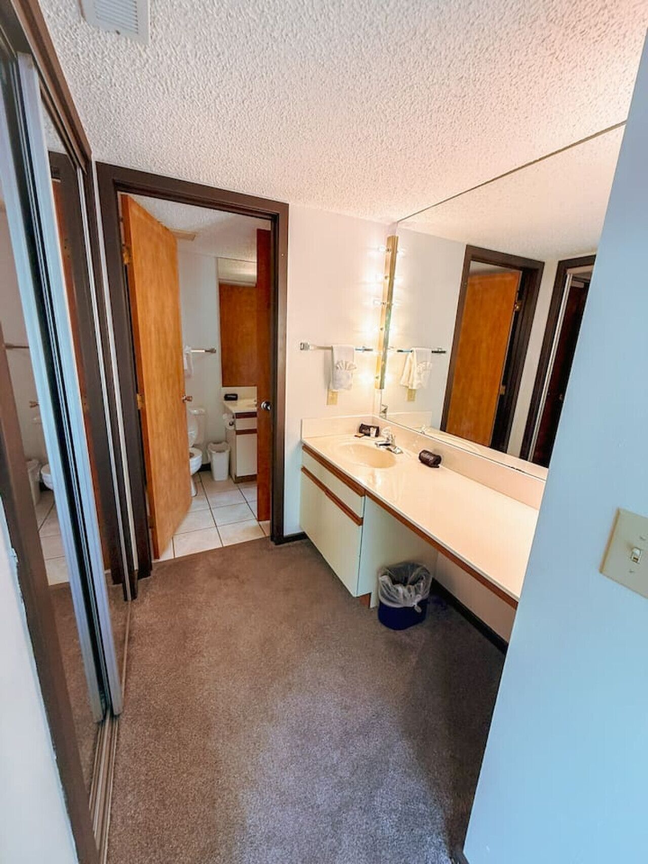 A compact bathroom with a sink, mirror, and toilet.