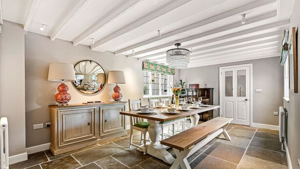 Una cocina con una isla central, muebles blancos y una araña.