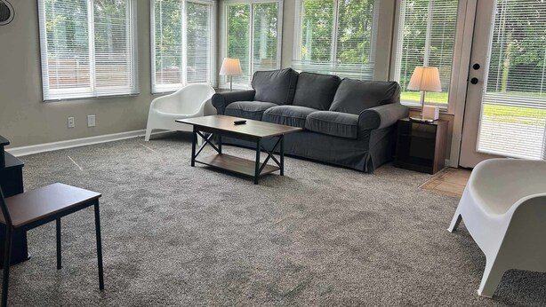 A living room with a gray sofa, a white chair, a small table, and a lamp. - Loveland Family Home: 3BR, 2 Living Areas, Free Parking (Loveland)
