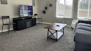 A living room with a flat-screen TV, two chairs, a coffee table, and a couch. - Loveland Family Home: 3BR, 2 Living Areas, Free Parking (Loveland)