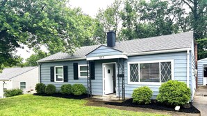 A single-story house with a dark blue exterior, a white door, and a chimney. - Loveland Family Home: 3BR, 2 Living Areas, Free Parking (Loveland)