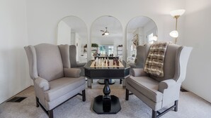A room with two armchairs, a coffee table, and three mirrors on the walls.