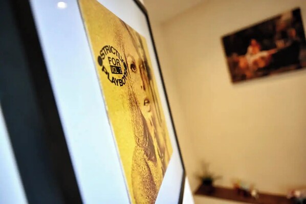 A room with a poster on the wall and a painting above it.