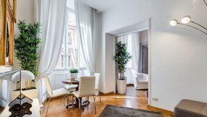 A modern living room with a dining area, a sofa, and a large window with sheer curtains. - Fabulous Cozy Pantheon Apartment (Roma)