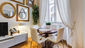 A dining area with a round table, white chairs, a TV on a white cabinet, and framed pictures on the wall. - Fabulous Cozy Pantheon Apartment (Roma)