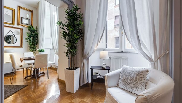 A well-lit room with a dining area, a sofa with a patterned pillow, and a potted plant. - Fabulous Cozy Pantheon Apartment (Roma)
