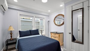 A bedroom with a bed, dresser, mirror, and window with blinds. - Two Bedroom Oceanside Condo Steps from the Beach (Ocean City)