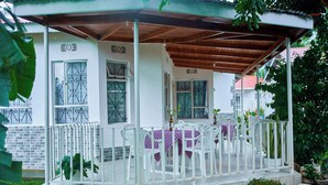 A covered outdoor seating area with white chairs and a table, surrounded by a white railing. - A Little Paradise in Arusha – Serenity with Stunning Mountain Views (Arusha)