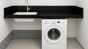 A compact laundry area with a washing machine and a sink under a black countertop. - A Little Paradise in Arusha – Serenity with Stunning Mountain Views (Arusha)