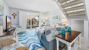 A living room with a sofa, coffee table, and a staircase. - Anchorage by the Sea Ocean View Balconies and Pool (Myrtle Beach)