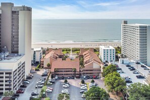 A multi-story hotel with a parking lot, a beach view, and a parking garage. - Anchorage by the Sea Ocean View Balconies and Pool (Myrtle Beach)