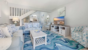 A living room with a staircase, a TV, and a patterned rug. - Anchorage by the Sea Ocean View Balconies and Pool (Myrtle Beach)