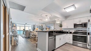 Una cocina moderna con armarios blancos, electrodomésticos de acero inoxidable y una isla central.
