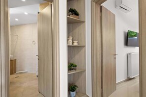 Een moderne badkamer met een douche, toilet en wastafel. Houten deuren en een witte muur met een tv.