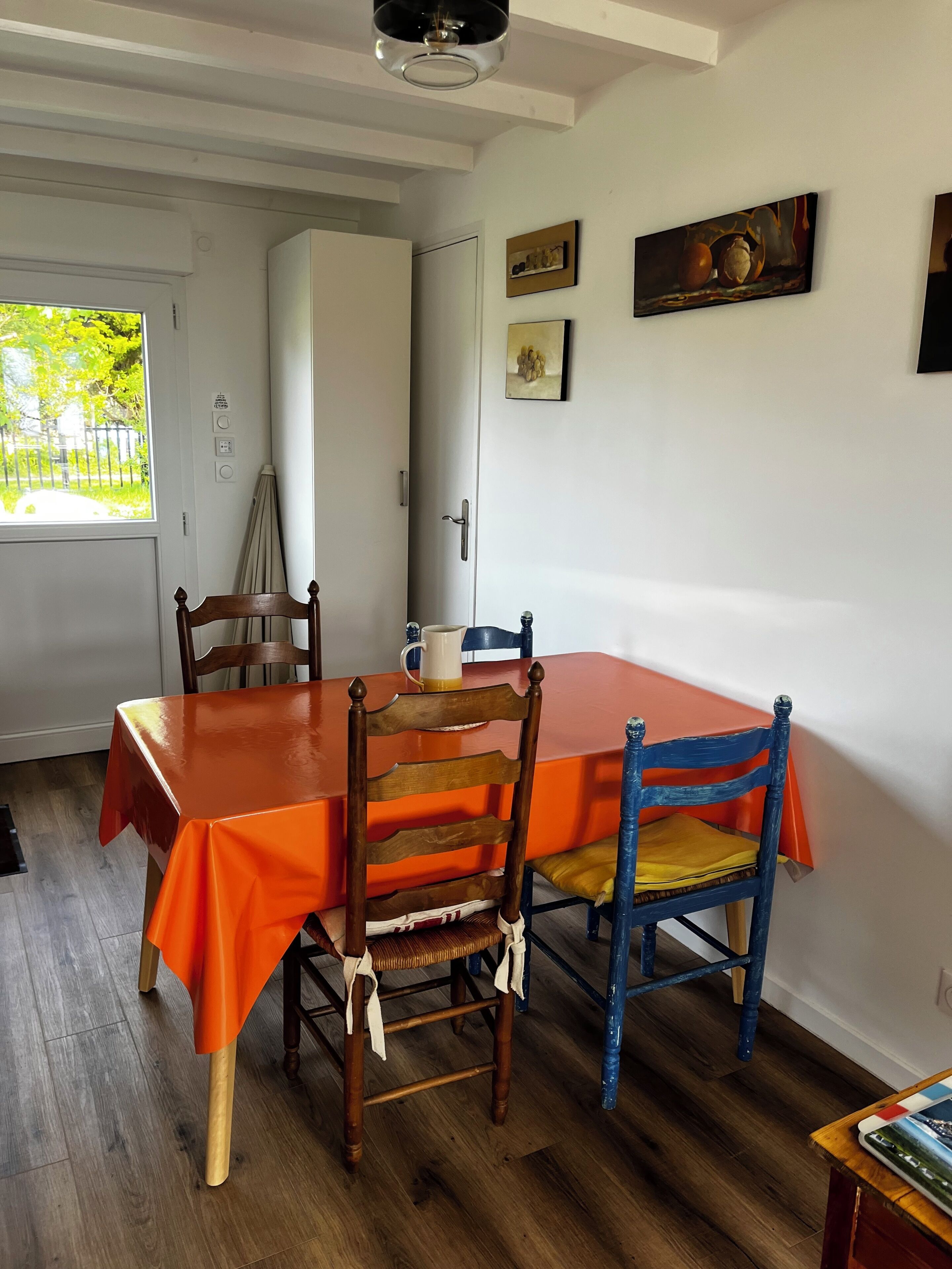 A dining area with a table, chairs, and artwork on the walls.