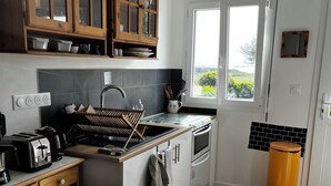 A kitchen with wooden cabinets, a sink, a stove, and a window.