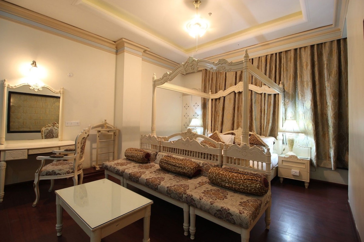 Une chambre à coucher avec un lit à baldaquin, une table de chevet, une chaise, un bureau et un miroir.