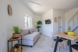 A modern living room with a sofa, a dining table with chairs, a small kitchen area, and a staircase. - Terra Nuova Zante in Zakynthos (Zakynthos)