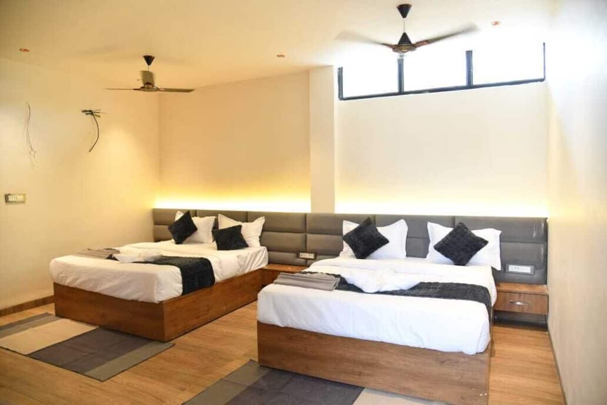 Una habitación de hotel con dos camas, un ventilador de techo y una mesita de noche.