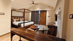 Habitación de hotel con cama con dosel, un banco de madera, una mesita pequeña y un ventilador de techo.