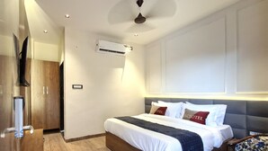 Una habitación de hotel moderna con una cama de madera, ventilador de techo, equipo de aire acondicionado y televisor.