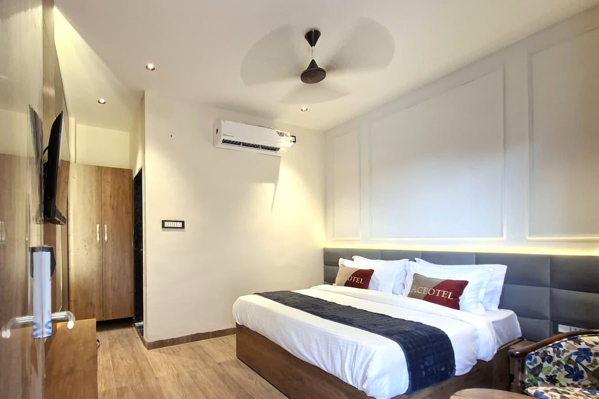 Una habitación de hotel moderna con una cama de madera, ventilador de techo, equipo de aire acondicionado y televisor.