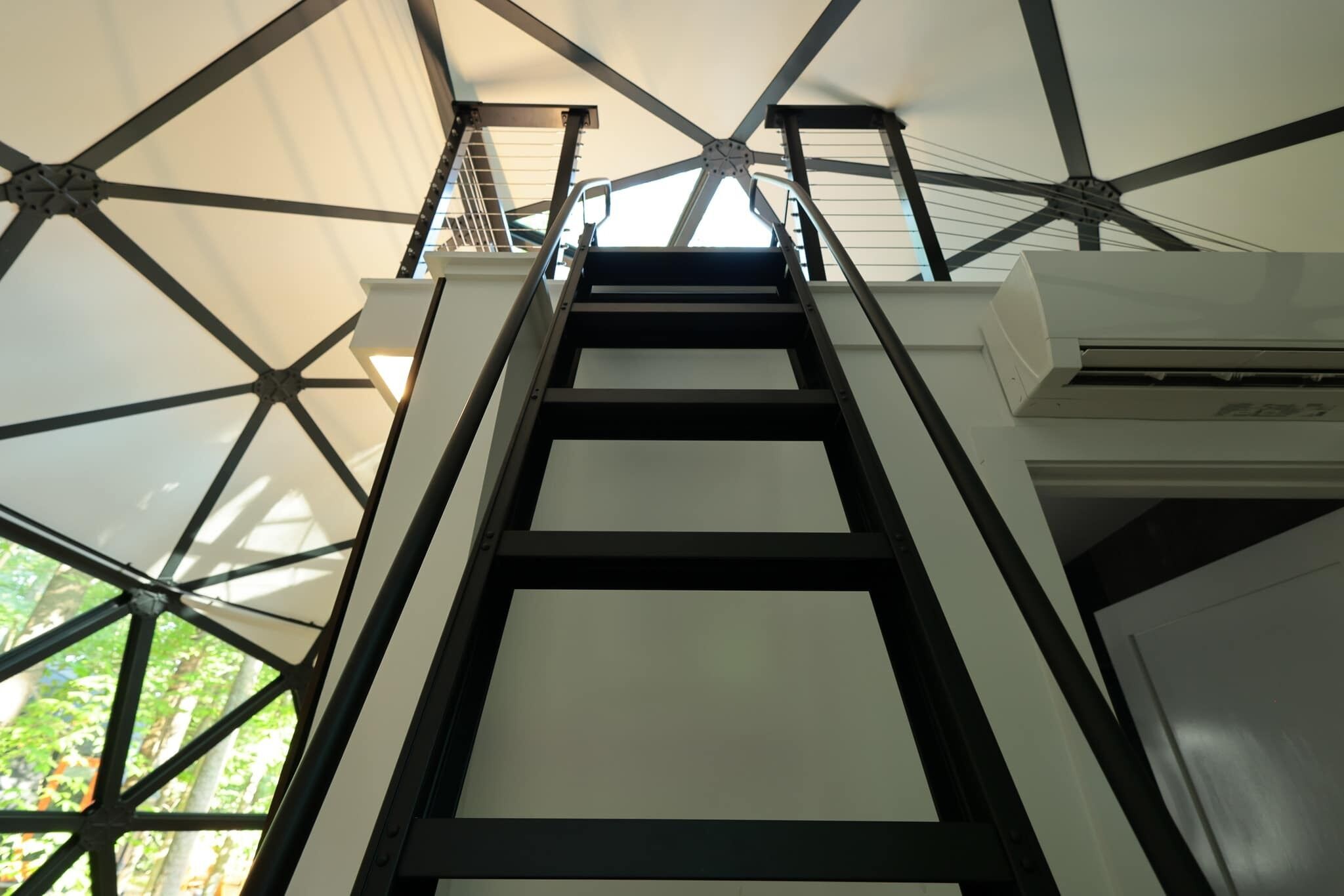 A staircase leading to a balcony with a view of greenery.